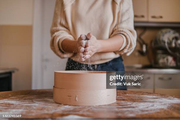 femme secouant la farine de ses mains - passoire photos et images de collection