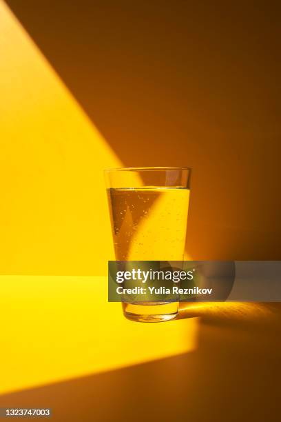 water in glas on the yellow background - glass shadow stockfoto's en -beelden