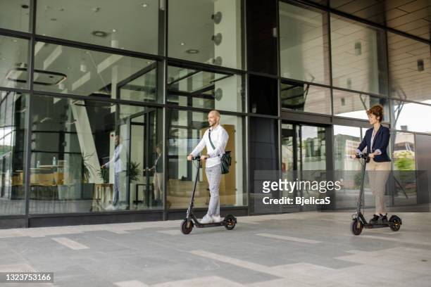 business colleagues riding e-scooters after work - youth culture speed stock pictures, royalty-free photos & images