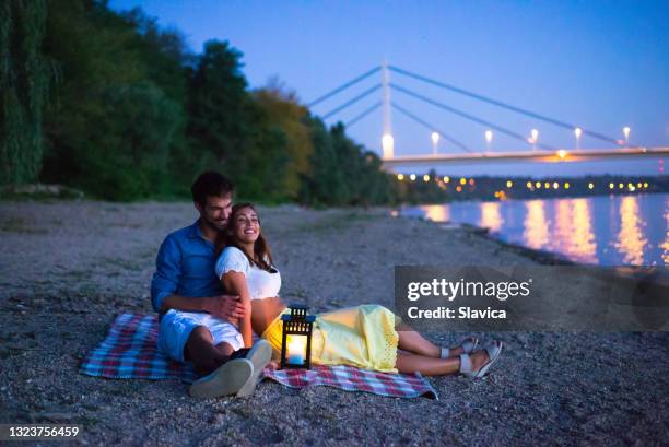 young happy couple on summer picnic on beach - night picnic stock pictures, royalty-free photos & images