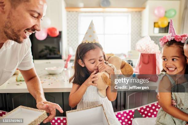 shot of a little girl opening her birthday present at home with her family - birthday present stockfoto's en -beelden