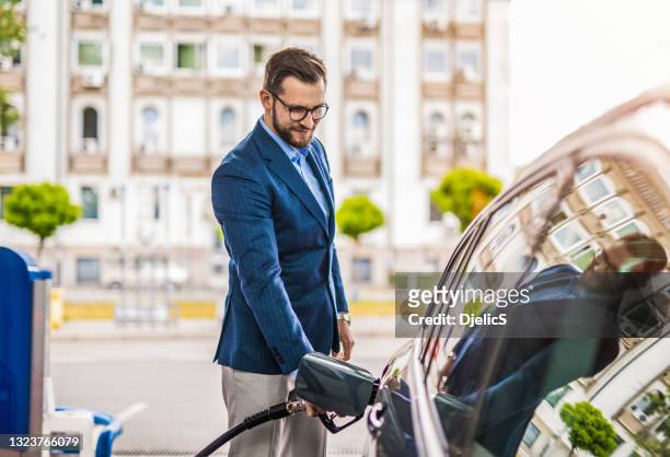 happy young man refueling his car the gas station. - filling petrol stock pictures, royalty-free photos & images