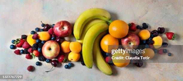 variety of fresh fruit on multi-colored background - strawberry banana stock pictures, royalty-free photos & images