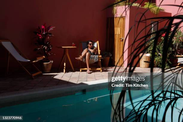 latin woman seated in a chair by swimming pool, looking at mobile phone - oaxaca state 個照片及圖片檔
