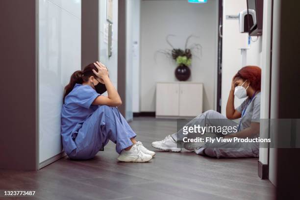 exhausted nurses take a break from their stressful shift - tired healthcare worker stock pictures, royalty-free photos & images