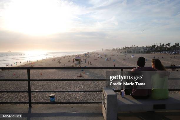 People sit on the Huntington Beach pier on June 15, 2021 in Huntington Beach, California. California, the first state in the U.S. To go into lockdown...