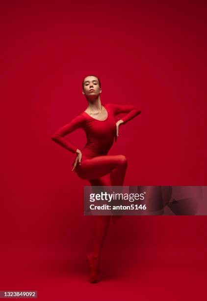 grácil joven hermosa chica, bailarina de ballet posando aislada sobre fondo rojo. - art modeling studio fotografías e imágenes de stock