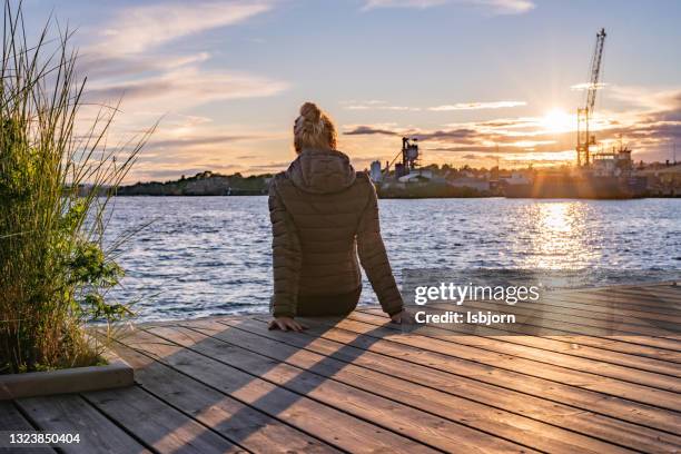 woman sitting on a pier and looking at view - oslo city life stock pictures, royalty-free photos & images