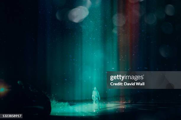 a mysterious ufo concept. of a man next to a car, standing in the middle of a road looking up at the night sky. as a glowing beam of light comes down from the sky. with a retro, grunge edit. - extraterrestrial stock pictures, royalty-free photos & images