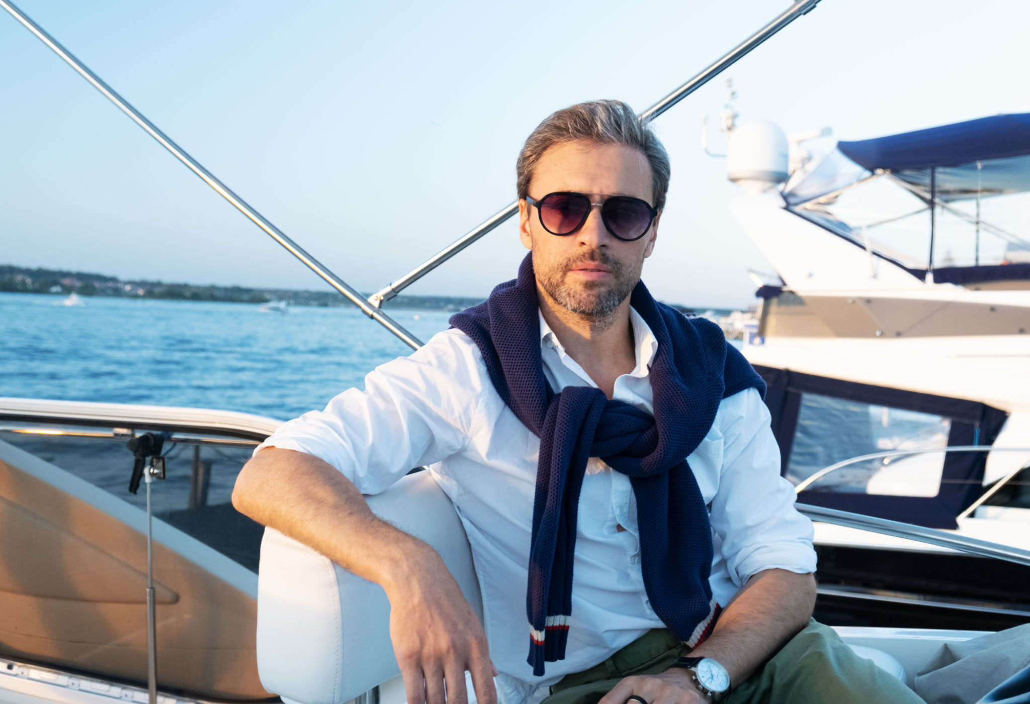Handsome good looking mature man on the yacht. Portrait of successful man on sailing boat at sunset. Handsome good looking mature man on the yacht. Portrait of successful man on sailing boat at sunset.