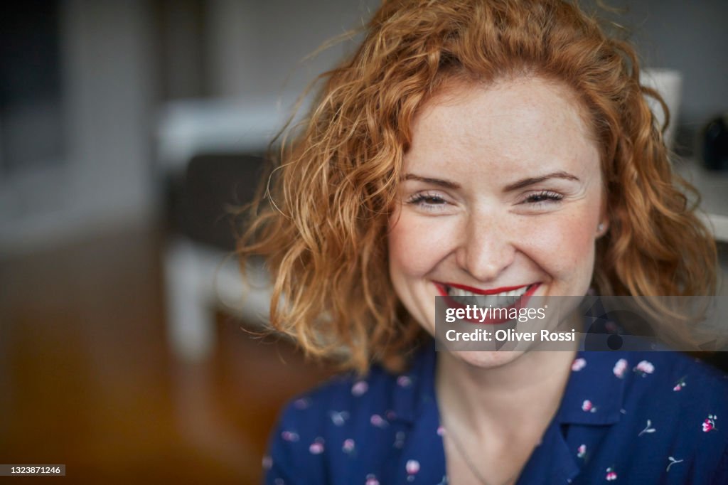 Portrait of happy redheaded woman at home
