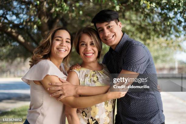 latin mother with two children standing outside and smiling - mature latin women stockfoto's en -beelden