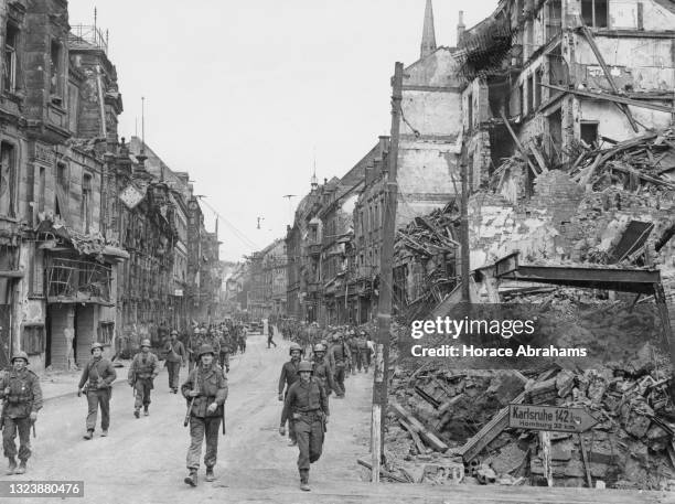 American infantrymen of the 276th US Infantry of 70th Infantry Division, United States 7th Army advance through the shell damaged city of Saarbrucken...