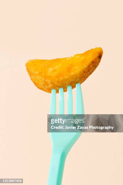 potato wedge on a turquoise fork on pastel background - fine art stock-fotos und bilder