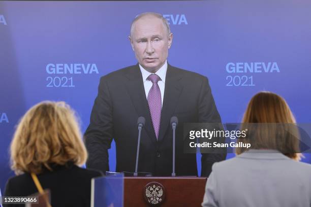 Journalists in the nearby media center watch live as Russian President Vladimir Putin speaks during a press conference at a hotel on the property of...