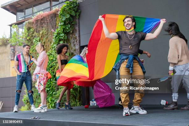 young man proudly displaying the gay flag. - gay pride parade stock pictures, royalty-free photos & images