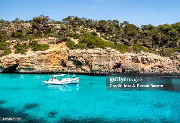 coastal landscape, yacht in a small cove with transparent turquoise blue waters in cala del moro, mallorca. - islas baleares fotografías e imágenes de stock