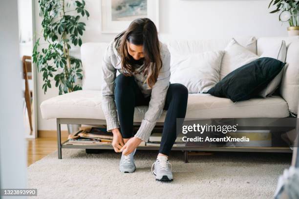 young woman gets dressed in activewear at home - aankleden stockfoto's en -beelden