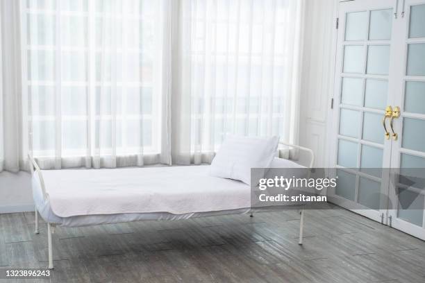 empty room with one bed set in front of door and glass windows with white curtain. it look like studio for photography or patient bed to service - duvet inners stock pictures, royalty-free photos & images