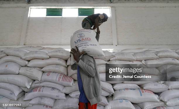 Aid workers move bags of yellow lentils that are part of athree-piece "Full Package" to be distributed to residents of Geha subcity at an aid...