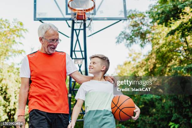 ein kleiner junge verbringt seine freizeit mit seinem großvater - basket ball stock-fotos und bilder