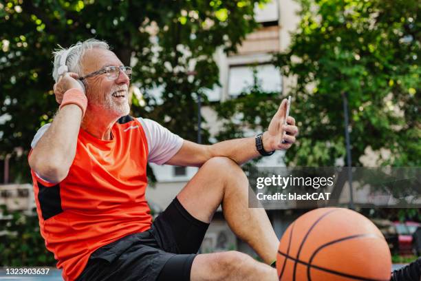 vital and happy senior man on the basketball field is using mobile phone - online court hearing stock pictures, royalty-free photos & images