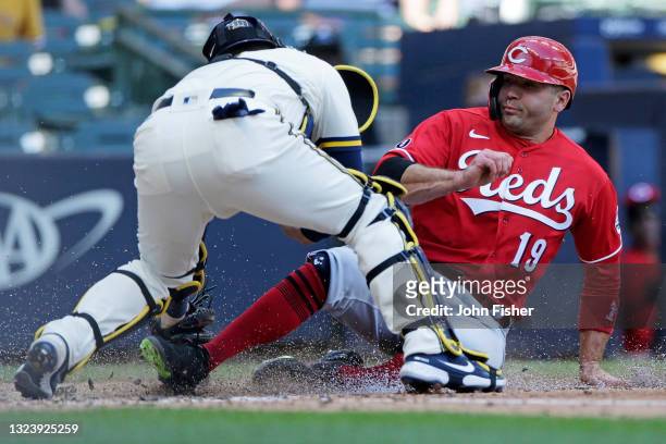 Joey Votto of the Cincinnati Reds slides safely into home plate in the seventh inning against the Milwaukee Brewers at American Family Field on June...