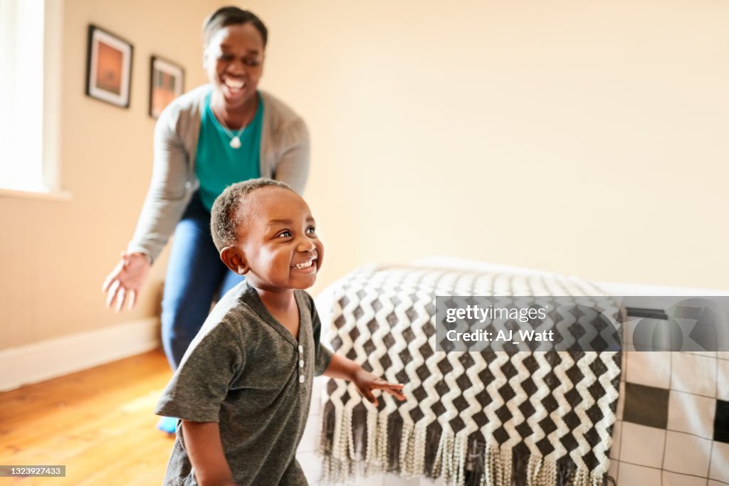 Girl playing with mother in bedroom at home