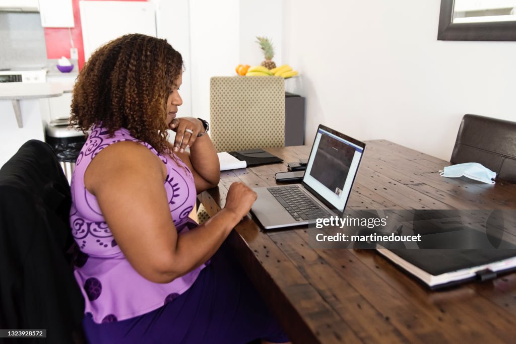 Mujer afroamericana madura que trabaja desde casa en teleconferencia.