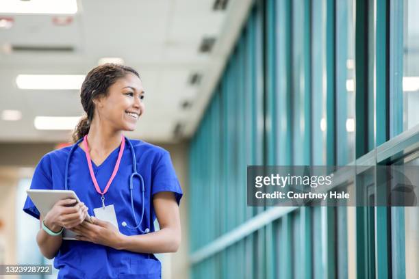 young female nurse looking out the hospital window smiling - medical student 個照片及圖片檔