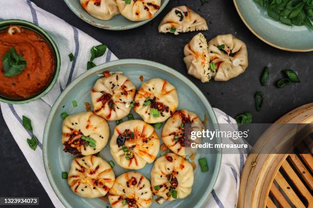 imagen de momos al vapor (albóndigas del sur de asia), harina blanca y masa de agua llena de carne de cerdo y verduras mezcladas, rociar con aceite de chile, junto al vapor de bambú, vista elevada - raviolis chinos fotografías e imágenes de stock