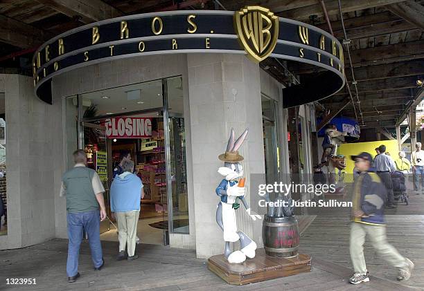 People walk by a statue of cartoon character Bugs Bunny, dressed as a fisherman, outside of a Warner Bros. Studio Store July 9, 2001 on Pier 39 in...