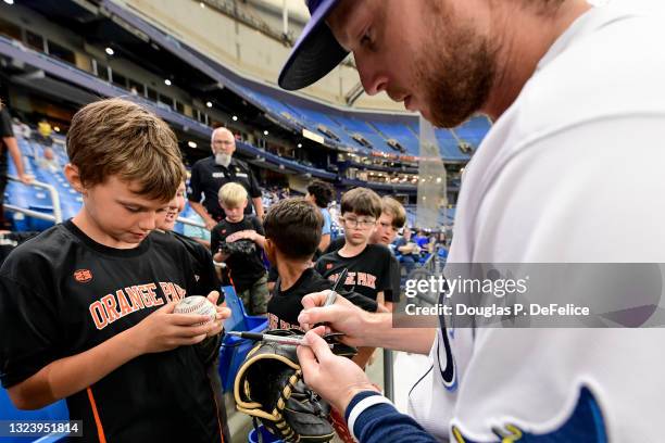 Brett Phillips of the Tampa Bay Rays signs autographs for fans prior to the game against the Baltimore Orioles at Tropicana Field on June 11, 2021 in...