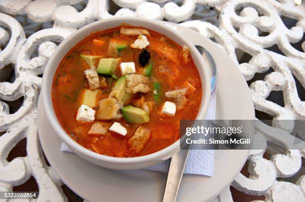 bowl of aztec soup (sopa azteca), also know as mexican tortilla soup, containing tomato, fried tortilla strips, avocado, panela cheese, chicharrón (fried pork rinds/skin) and dried chili pepper - chili soup stock pictures, royalty-free photos & images