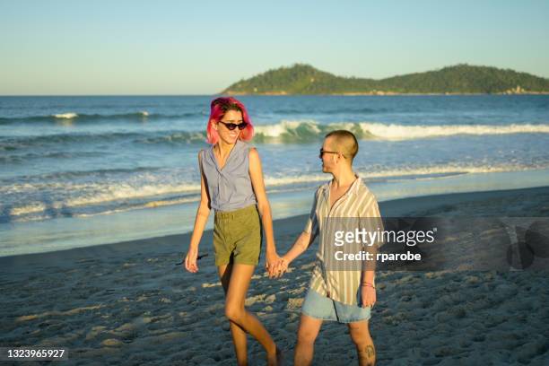 Transgender couple wearing sunglasses on the beach