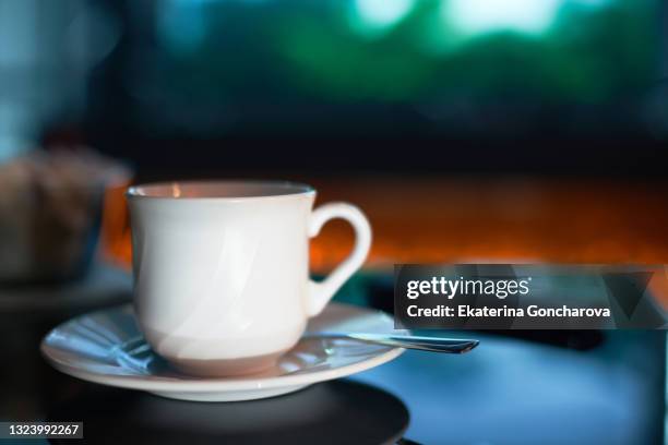 a white cup of coffee or tea in the waiting room of a car wash on the blurred background of the tv. - car wash cafe stock pictures, royalty-free photos & images