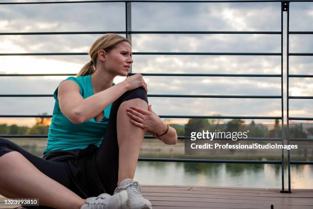 young female athlete is having knee problems while jogging in the city - meniscus stock pictures, royalty-free photos & images