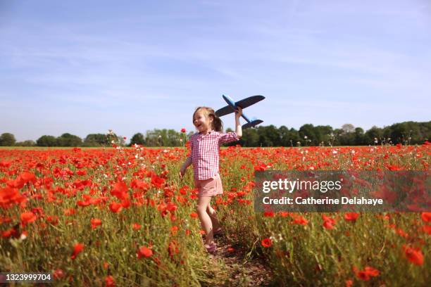 a girl playing with a plane in a poppy field - bright future stock pictures, royalty-free photos & images