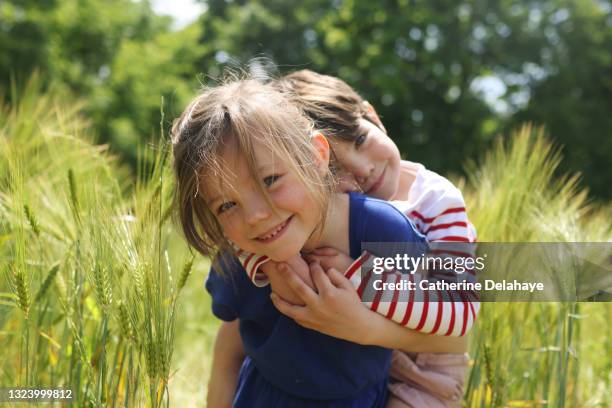 a girl carrying her little brother in a wheat field - sister photos et images de collection