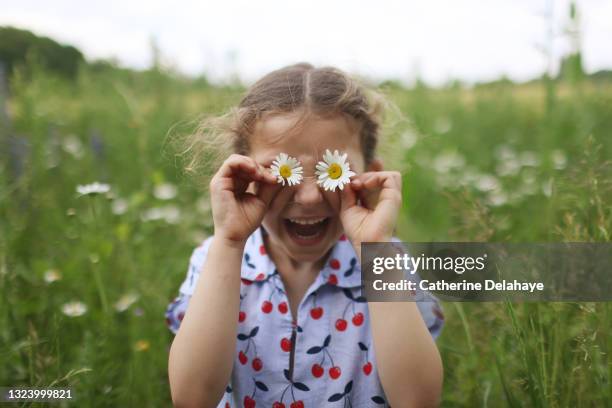 a 5 year girl playing with daisies in a field - happy children foto e immagini stock