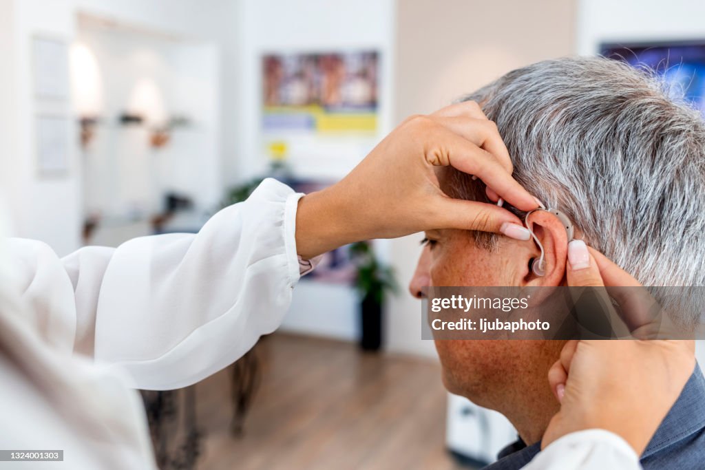 Femme médecin équid’un patient masculin d’une aide auditive