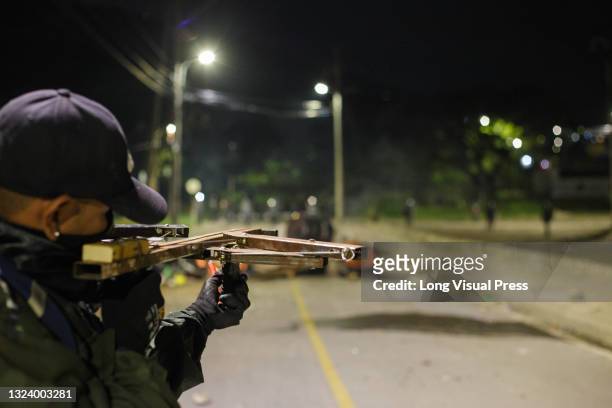 Demonstrator aims a handcrafted crossbow at police as demonstrators and Colombia's riot police clash during the night of June 14 in Yumbo - Cali,...