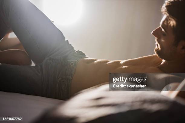 handsome man resting on a bed. - alluring stock pictures, royalty-free photos & images