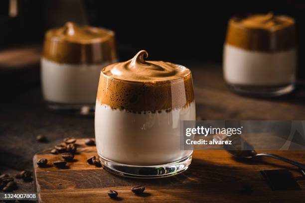 dalgona coffee with coffee beans on table - toetje stockfoto's en -beelden