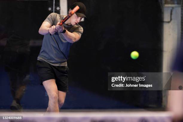 man playing padel at indoor court - paddle tennis stock pictures, royalty-free photos & images