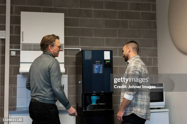 coworkers talking near coffee machine - coffee machine stock pictures, royalty-free photos & images