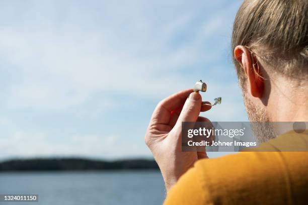 man taking off hearing aid - hearing aid stock pictures, royalty-free photos & images