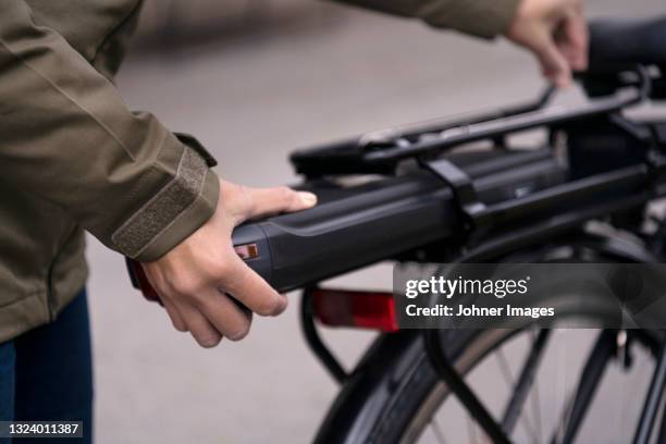 woman fitting battery on electric bike - e bike stock pictures, royalty-free photos & images