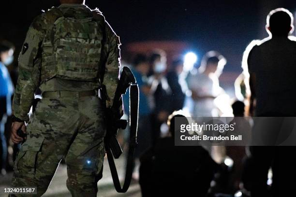Member of the National Guard stand watch while immigrants wait to be processed after crossing the Rio Grande into the U.S. On June 16, 2021 in Roma,...