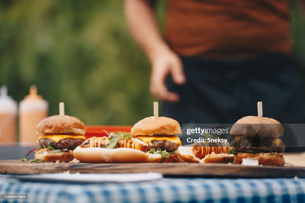 Hot dogs and hamburgers placed on chopping board.